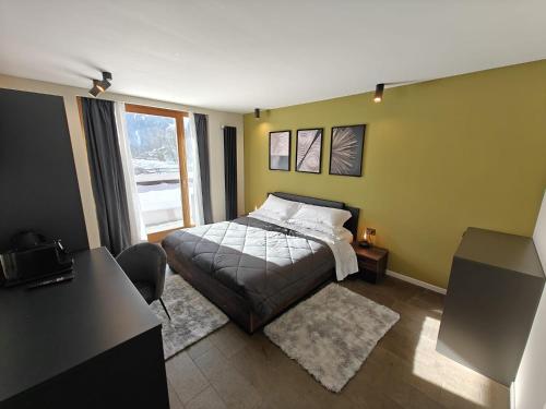 a bedroom with a bed and a desk and a window at Hotel La Thuile Resort & SPA in La Thuile
