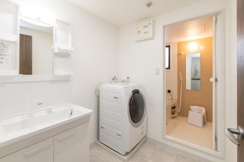 a white bathroom with a washing machine and a sink at Atrium Deluxe Apartments Osaka - Self Check-In Only in Osaka