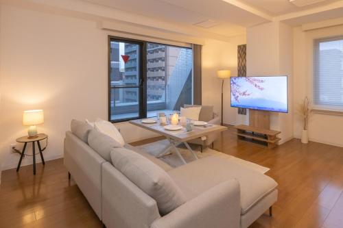 a living room with a couch and a table and a tv at Atrium Deluxe Apartments Osaka - Self Check-In Only in Osaka