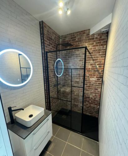 La salle de bains est pourvue d'un lavabo blanc et d'un mur en briques. dans l'établissement La Ch'tite Cahute, à Ambleteuse