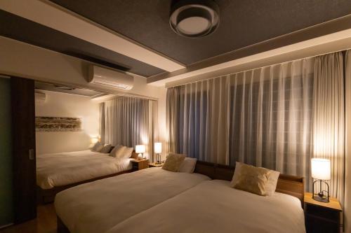 a hotel room with two beds and two lamps at Atrium Deluxe Apartments Osaka - Self Check-In Only in Osaka