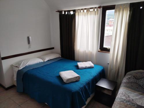 a bedroom with a blue bed with two towels on it at Departamento Centro Ushuaia in Ushuaia