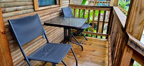 two chairs and a table on the porch of a cabin at Tuquil-HA in Ladyville