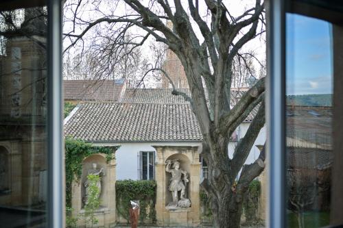 a window view of a building with a statue next to a tree at Hôtel Paul in Aix-en-Provence