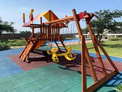 a playground with a slide in front of a pool at CASASANTA Fe cercalberca Wifi in Alpuyeca