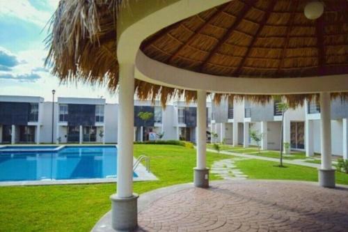 a building with a large umbrella and a swimming pool at CASASANTA Fe cercalberca Wifi in Alpuyeca