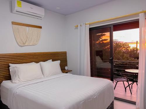 a bedroom with a white bed and a balcony at Monstera Apartments Monteverde in Monteverde Costa Rica