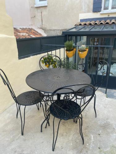 une table noire et des chaises sur un balcon dans l'établissement Calussine maison provençale, à Pernes-les-Fontaines