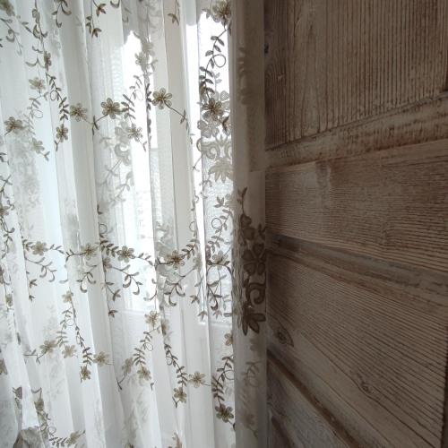 a window with a white curtain with flowers on it at ROSSINI GUEST HOUSE in Martina Franca