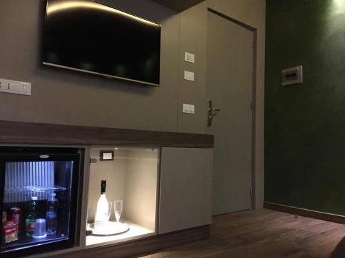 a room with a tv and a display case with wine glasses at Hotel Smeraldo in Qualiano