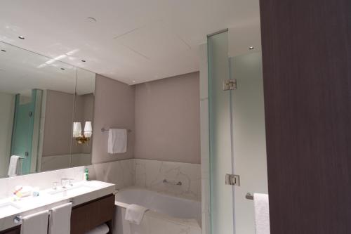 a bathroom with a tub and a sink and a mirror at Address Residence Bahrain in Rayyā
