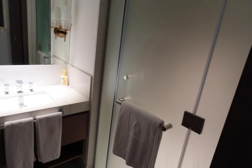 a bathroom with a sink and a mirror and towels at Address Residence Bahrain in Rayyā
