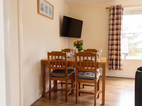a dining room table with chairs and a television at Stouts Court Apartment in Lerwick