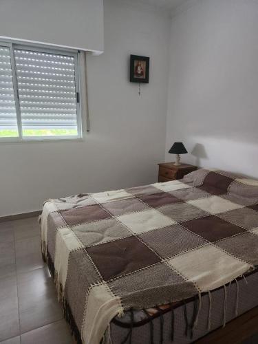 a bedroom with a bed with a checkered blanket on it at Duplex en Gualeguay in Gualeguay