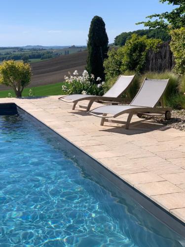 two lounge chairs sitting next to a swimming pool at Les 5 terrasses - vue imprenable et piscine privée in La Sauvetat
