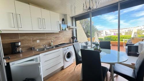 une cuisine avec une machine à laver et une table dans l'établissement NATURISME LE CAP D'AGDE APPART. 4 PERSONNES D 63, au Cap d'Agde