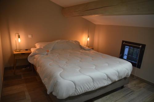 un grand lit blanc dans une chambre avec une fenêtre dans l'établissement Appartement au coeur des Alpilles, à Mas blanc des Alpilles
