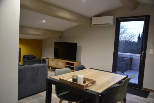 un salon avec une table, des chaises et une télévision dans l'établissement Appartement au coeur des Alpilles, à Mas blanc des Alpilles