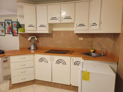 a kitchen with white cabinets and a sink at Arco Iris Atacames in Atacames