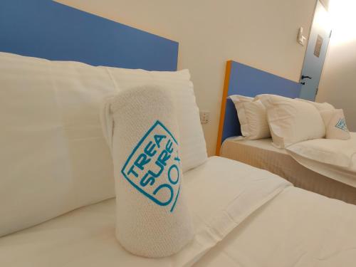 a white bed with a pillow with a sign on it at TREASURE BOX At Heritage Georgetown in George Town