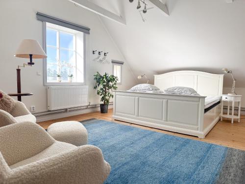 a bedroom with a bed and two chairs and a blue rug at STUBBET - Charming - Newly Remade Villa in Vadstena