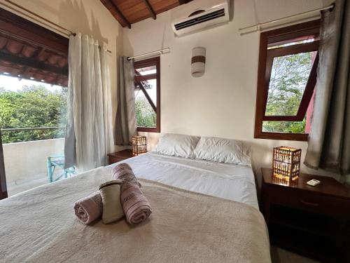 Casa Dendê - Arraial D'Ajuda في ارايال دايودا: غرفة نوم بها سرير كبير مع مناشف عليه