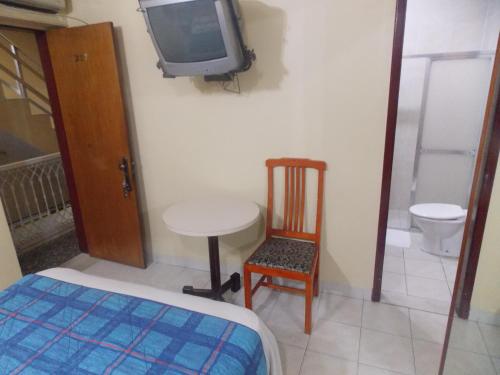 a room with a table and a tv and a chair at Hotel Caxambu in Rio de Janeiro