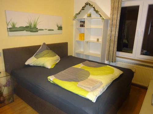 a bed with two pillows and a yellow blanket at Ferienwohnung LAN in Bad Rothenfelde