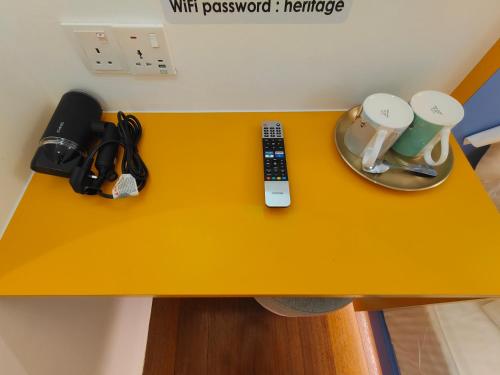 a yellow table with a remote control and cups on it at TREASURE BOX At Heritage Georgetown in George Town