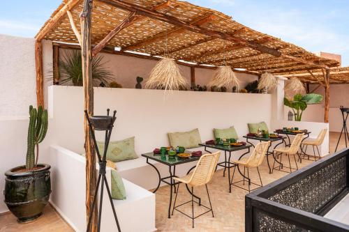 a patio with tables and chairs under a pergola at Riad Dar Acsameda & Spa in Marrakech