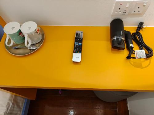 a yellow table with a phone and a remote control at TREASURE BOX At Heritage Georgetown in George Town