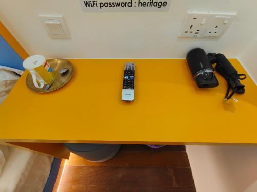 a yellow table with a remote control and a telephone at TREASURE BOX At Heritage Georgetown in George Town