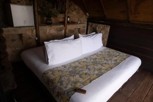 a bedroom with a bed with white sheets and pillows at REFUGIO LA ROCA in Los Santos