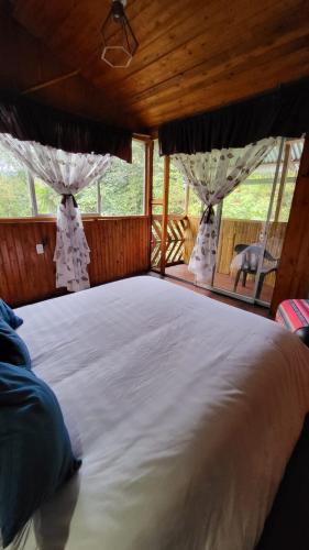 a large bed in a room with windows at Mindo GlamBird Glamping & Lodge in Mindo