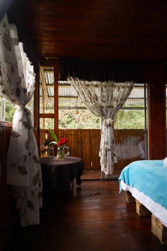 a bedroom with curtains and a bed and a table at Mindo GlamBird Glamping & Lodge in Mindo