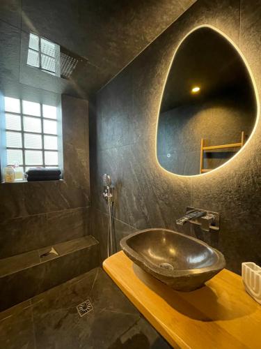 La salle de bains est pourvue d'un lavabo et d'un miroir rond. dans l'établissement Apparemment luxueux niché dans les arbres, à Narbonne