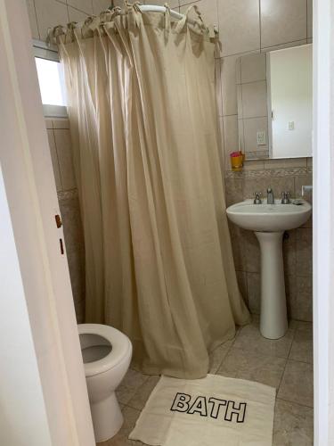 a bathroom with a shower curtain and a toilet and a sink at CerroSur in Yacimiento Río Turbio