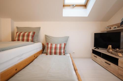 a small room with a bed and a flat screen tv at Schwalbennest Velden in Velden am Wörthersee