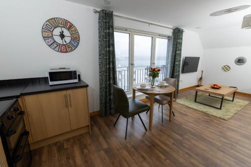 a living room with a table and a clock on the wall at Lerwick Penthouse Apartment in Lerwick