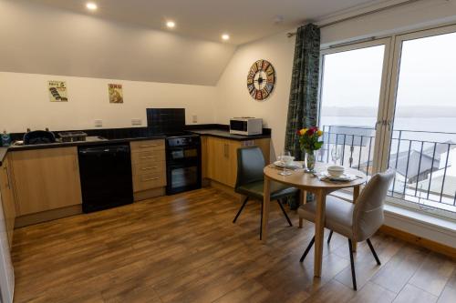 a kitchen and dining room with a table and a balcony at Lerwick Penthouse Apartment in Lerwick