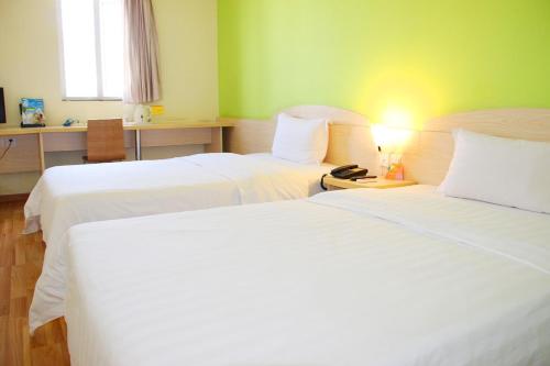 a hotel room with two beds and a desk at 7Days Inn Dongguan Houjie Conference & Exhibition Center in Dongguan