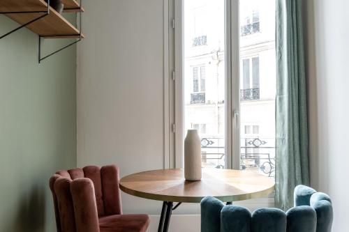 une table et des chaises dans une pièce avec une fenêtre dans l'établissement Appartement Cozy à Paris, à Paris