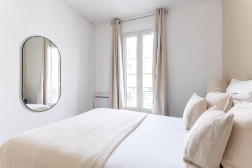 - une chambre blanche avec un grand lit blanc et un miroir dans l'établissement Appartement Cozy à Paris, à Paris