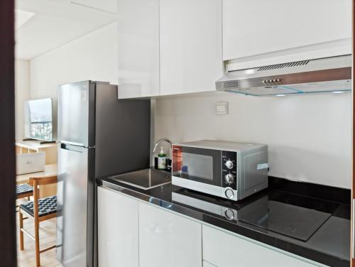 Una cocina con refrigerador de acero inoxidable y microondas. en Newly South Gate Studio Apt with Pool, Gym Netflix by 2ndHome, en Yakarta