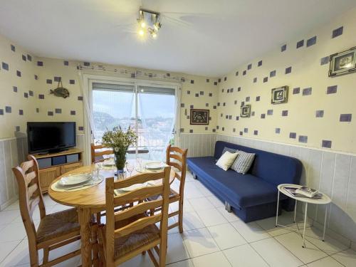 a living room with a table and a blue couch at Appartement familial proche des plages in Mimizan-Plage