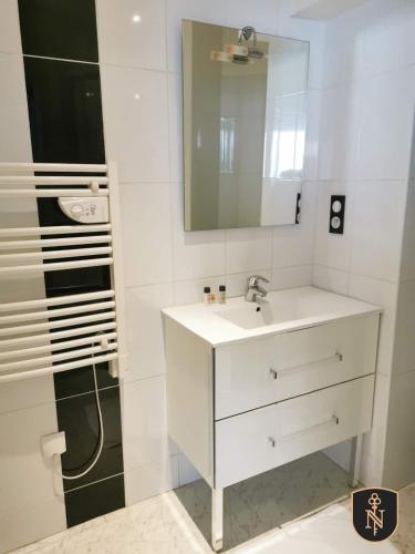 une salle de bain blanche avec un lavabo et un miroir dans l'établissement Magnifique appartement entre centre ville et gare - 5, au Mans