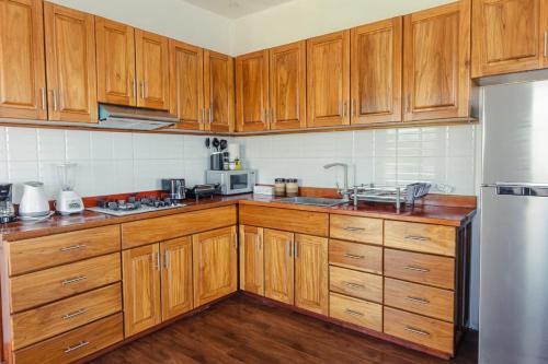 a kitchen with wooden cabinets and a stainless steel refrigerator at Chango's Apartments in Bocas del Toro