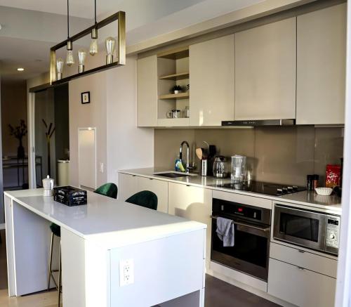 eine Küche mit weißen Schränken und einer weißen Arbeitsplatte in der Unterkunft Stunning suite in downtown perfect for businesses trips and small families in Toronto