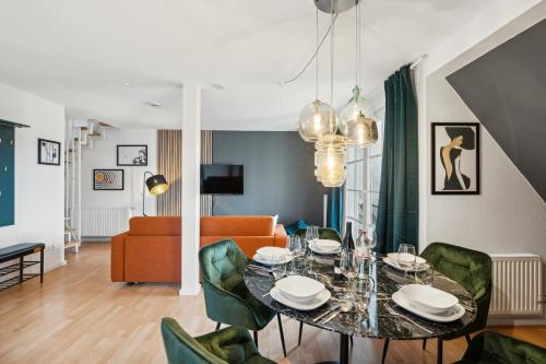 a dining room with a table and green chairs at maremar - Design-Maisonette am Holzmarkt - Luxus Boxspringbetten - Arbeitsplatz - Loggia in Verden