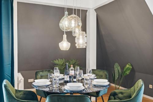 a dining room with a table and green chairs at maremar - Design-Maisonette am Holzmarkt - Luxus Boxspringbetten - Arbeitsplatz - Loggia in Verden